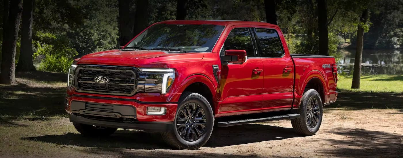 Red 2026 Ford F-150 parked off-road on a dirt road.